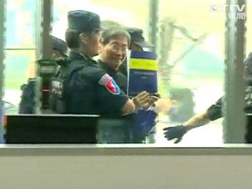 圖為“白狼”張安樂抵臺遭警方上銬押解